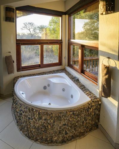 a large bath tub in a room with windows at Leopard's Lair Bush Lodge in Hoedspruit