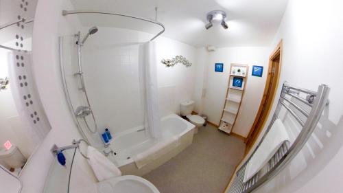 a bathroom with a tub and a shower and a toilet at Inverness City Centre Apartment with Elevator and Google Chromecast in Inverness