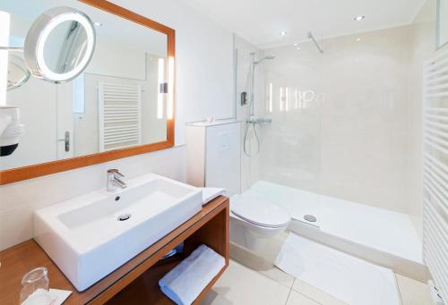 a bathroom with a sink and a toilet and a mirror at Hotel & Spa Sonne in Sankt Kanzian