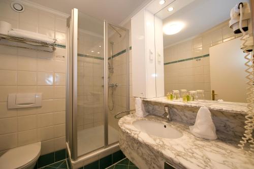 a bathroom with a sink and a shower and a toilet at Hotel & Spa Sonne in Sankt Kanzian