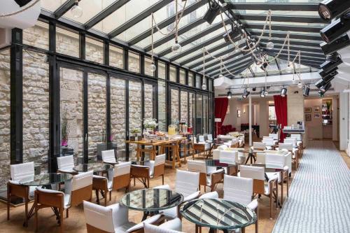 a restaurant with white chairs and tables and windows at Le 123 S&eacute;bastopol - Astotel in Paris