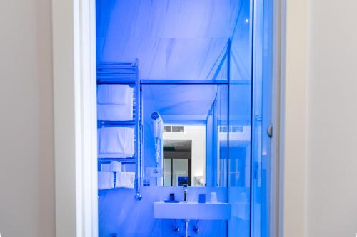 ein blaues Badezimmer mit Waschbecken und Spiegel in der Unterkunft Villa Zaccardi in Rom