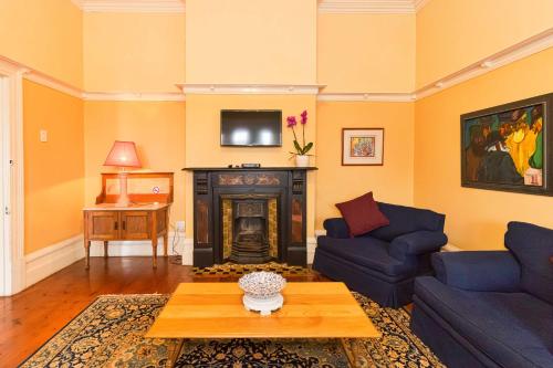 a living room with two blue couches and a fireplace at Fernando's self catering cottages in Port Elizabeth