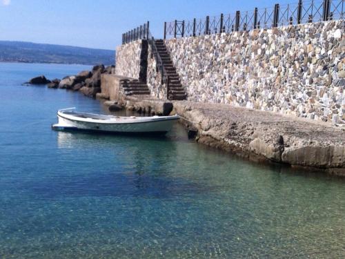 a boat sitting in the water next to a stone wall at B&B Il Vicolo Di Pizzo in Pizzo