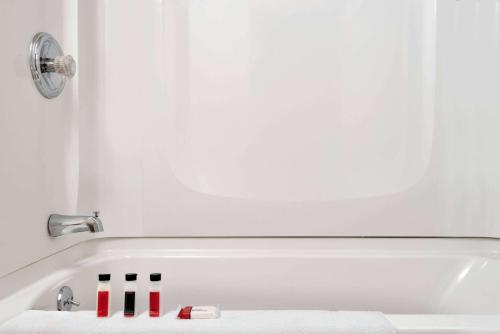a bathroom with a bath tub with some cosmetics at Super 8 by Wyndham Liverpool/Syracuse North Airport in Liverpool