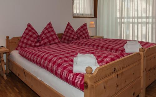 a bed with red plaid sheets and white towels on it at Chesa Guardamunt in Celerina