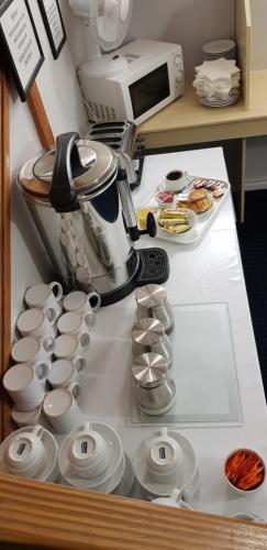 a kitchen counter with a coffee maker and cups at Redwings Lodge Dunstable in Dunstable