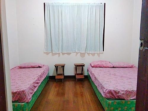 2 camas en una habitación con ventana en P&M Traveler's Inn, en Banaue