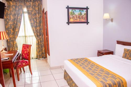 1 dormitorio con cama, escritorio y silla en Hôtel Prince De Galles, en Douala