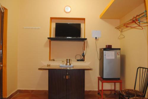 Zimmer mit einem TV und einem kleinen Kühlschrank. in der Unterkunft Joe And Marietta's Guesthouse in Calangute
