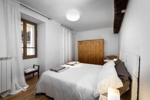 a bedroom with a white bed and a window at Al vicolo del Gallo APPARTAMENTO in Varallo