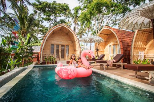 two women sitting on a pink rubber duck in a swimming pool at Puri Lumbung Village in Payangan