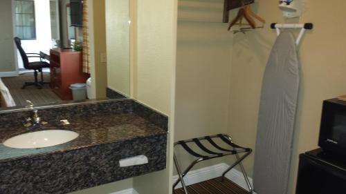 a bathroom with a sink and a mirror and a chair at Regency Inn in Moreno Valley