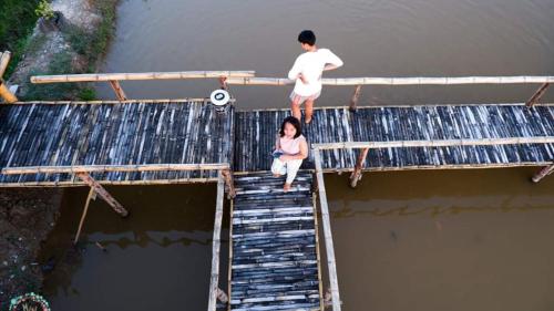 a man and a woman on a bridge over water at บวกบัววิวรีสอทร์ in Nan
