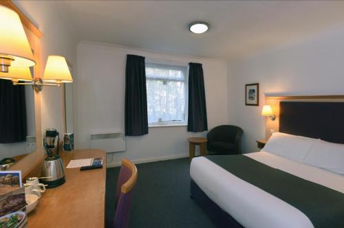 a hotel room with a bed and a desk and a bed and a desk at Lea Gate by Greene King Inns in Preston