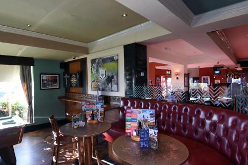 a bar with two tables and a leather couch at Lea Gate by Greene King Inns in Preston