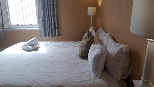 a bed with white sheets and pillows and a window at Fernando's self catering cottages in Port Elizabeth