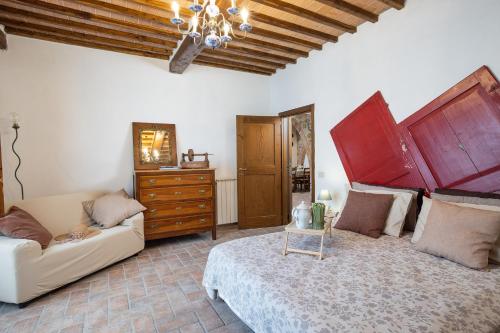 a living room with a bed and a couch at Casale del Bosco by VacaVilla in Casole dʼElsa