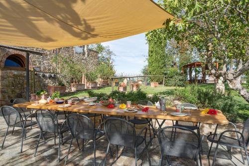 a wooden table and chairs under a yellow umbrella at Casale del Bosco by VacaVilla in Casole dʼElsa