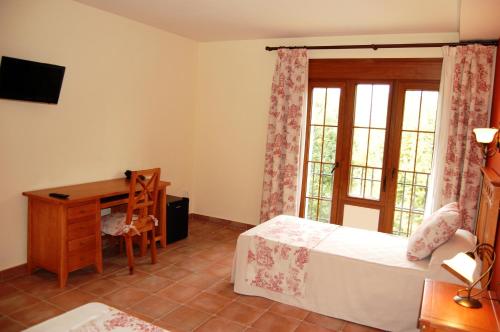 a bedroom with a desk and a bed and a window at Hotel El Cortijo de Daimiel in Daimiel