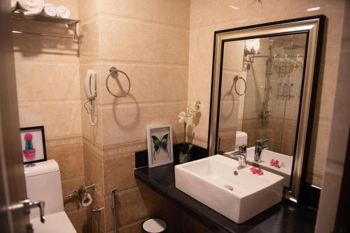 a bathroom with a sink and a mirror and a toilet at Sonia Hotel in Ouagadougou