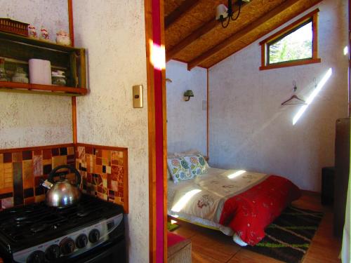 a kitchen with a stove and a bed in a room at Refugio de Montaña Kultrun Mawida, Cabaña Mirador in Curacautín