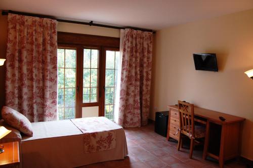a bedroom with a bed and a desk and a window at Hotel El Cortijo de Daimiel in Daimiel