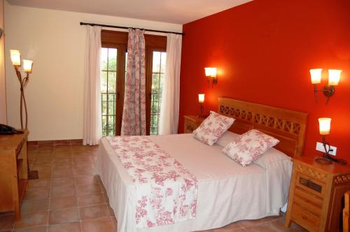 a bedroom with a large bed with red walls at Hotel El Cortijo de Daimiel in Daimiel