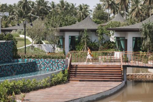 a woman walking down the stairs in front of a house at Na Tree Tara Riverside Resort Amphawa Damnoensaduak in Amphawa