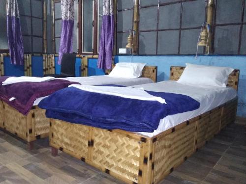 two twin beds in a room with purple curtains at N R Resort Kaziranga in Kāziranga