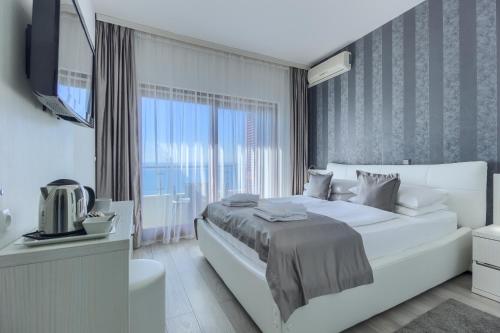 a white bedroom with a large bed and a television at Pansion Martin in Podstrana