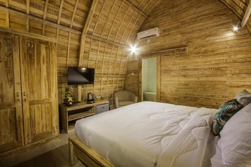 a bedroom with a bed in a room with wooden walls at Puri Lumbung Village in Payangan