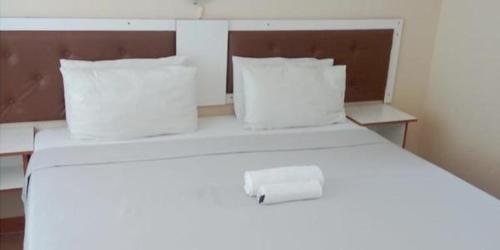 Una cama blanca con dos almohadas y una caja. en Amafana Guest House, en Mount Frere