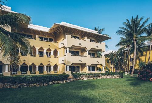 a large yellow building with palm trees in front of it at Iberostar Waves Paraíso del Mar in Puerto Morelos