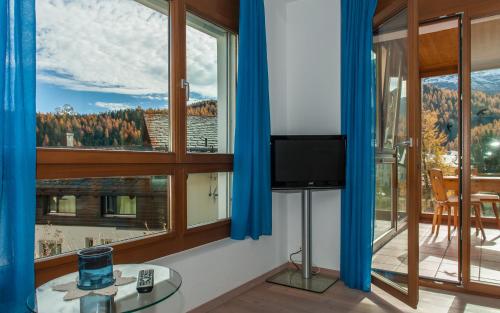 a room with large windows with a tv and a table at Chesa Guardamunt in Celerina
