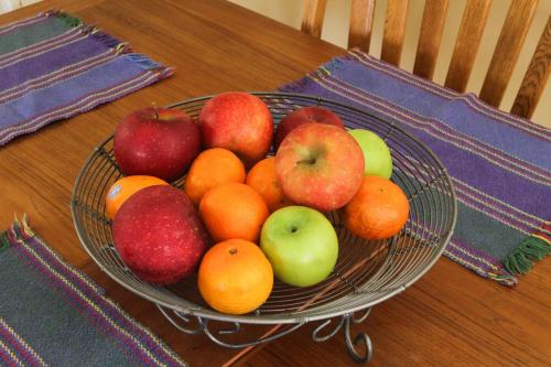 a bowl of fruit on a table with apples and oranges at Fairhaven Guesthouse in Charlottesville