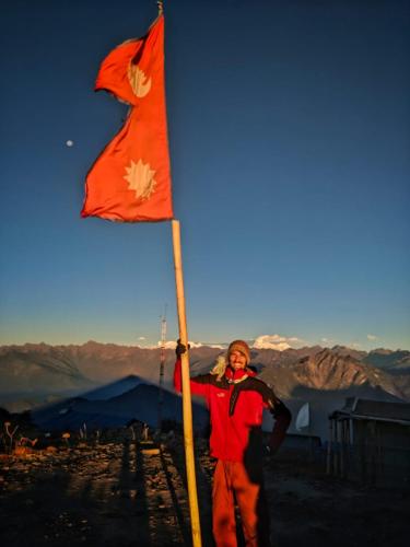 a person holding a flag on top of a mountain at Yog Hostel- Rooftop Yoga & Backpacker Social Stay in Thamel, Kathamndu in Kathmandu