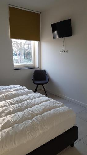 sypialnia z łóżkiem, krzesłem i telewizorem w obiekcie Hoeve Kroonen w mieście Schin op Geul