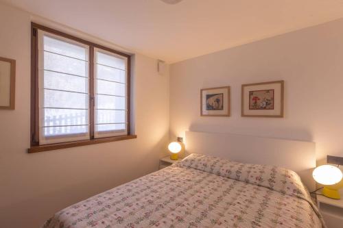 ein Schlafzimmer mit einem Bett, zwei Lampen und einem Fenster in der Unterkunft ALTIDO Warm Flat for 4, with Parking in Courmayeur in Courmayeur