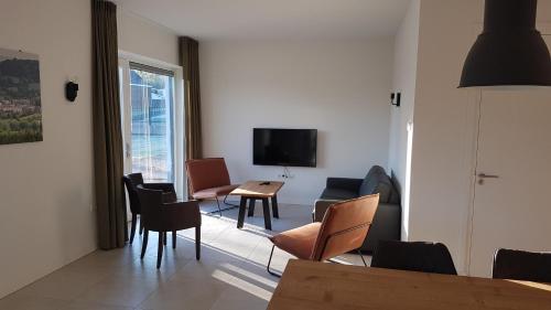 a living room with chairs and a table and a television at Hoeve Kroonen in Schin op Geul