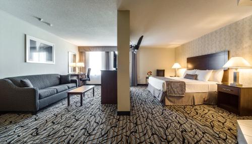 a hotel room with a bed and a couch at Monte Carlo Inn Oakville Suites in Oakville