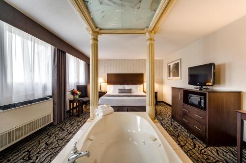 a hotel room with a tub and a bed at Monte Carlo Inn Oakville Suites in Oakville