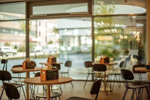 a restaurant with tables and chairs and a window at Holiday Inn - the niu, Mesh Stuttgart Messe by IHG in Stuttgart