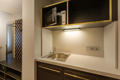 a kitchen with a sink and a microwave at Holiday Inn - the niu, Mesh Stuttgart Messe by IHG in Stuttgart