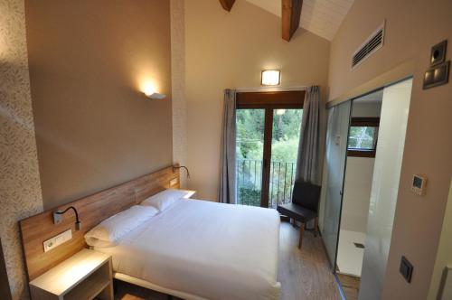 a bedroom with a bed and a desk and a window at Camping Valle de Bujaruelo in Torla-Ordesa