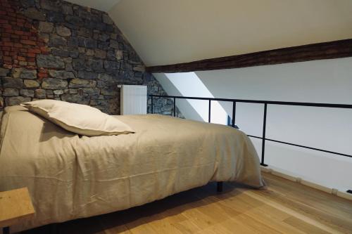 een slaapkamer met een bed en een stenen muur bij Le Parvis - Résidence Le Cercle in Marche-en-Famenne