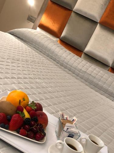 a tray of fruit on a bed with two cups at Il Feudo Di Agnadello in Agnadello