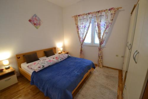 a bedroom with a bed with blue sheets and a window at Apartmani Antonia Nakić -Stobreč in Split