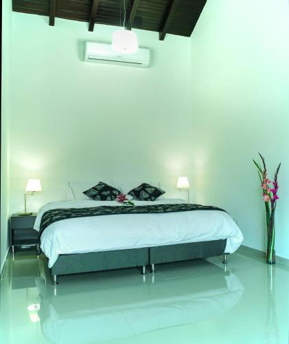 a bedroom with a large bed and a vase of flowers at La Cabrera Hotel Boutique in Neiva