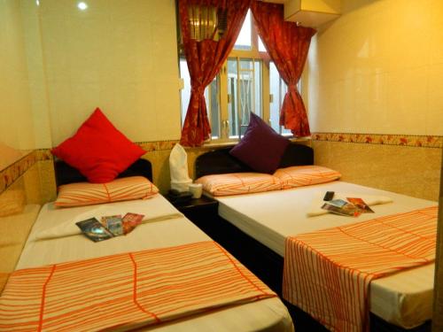 2 letti in una camera con tende rosse di New London Hostel a Hong Kong